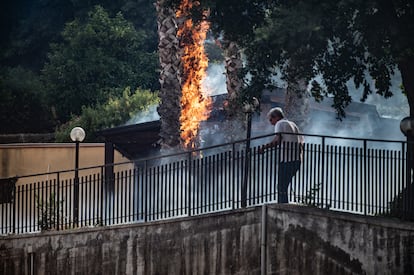 Un hombre intenta apagar el tronco de un árbol en llamas en la localidad de Aci Catena, cerca de Catania, este martes. 