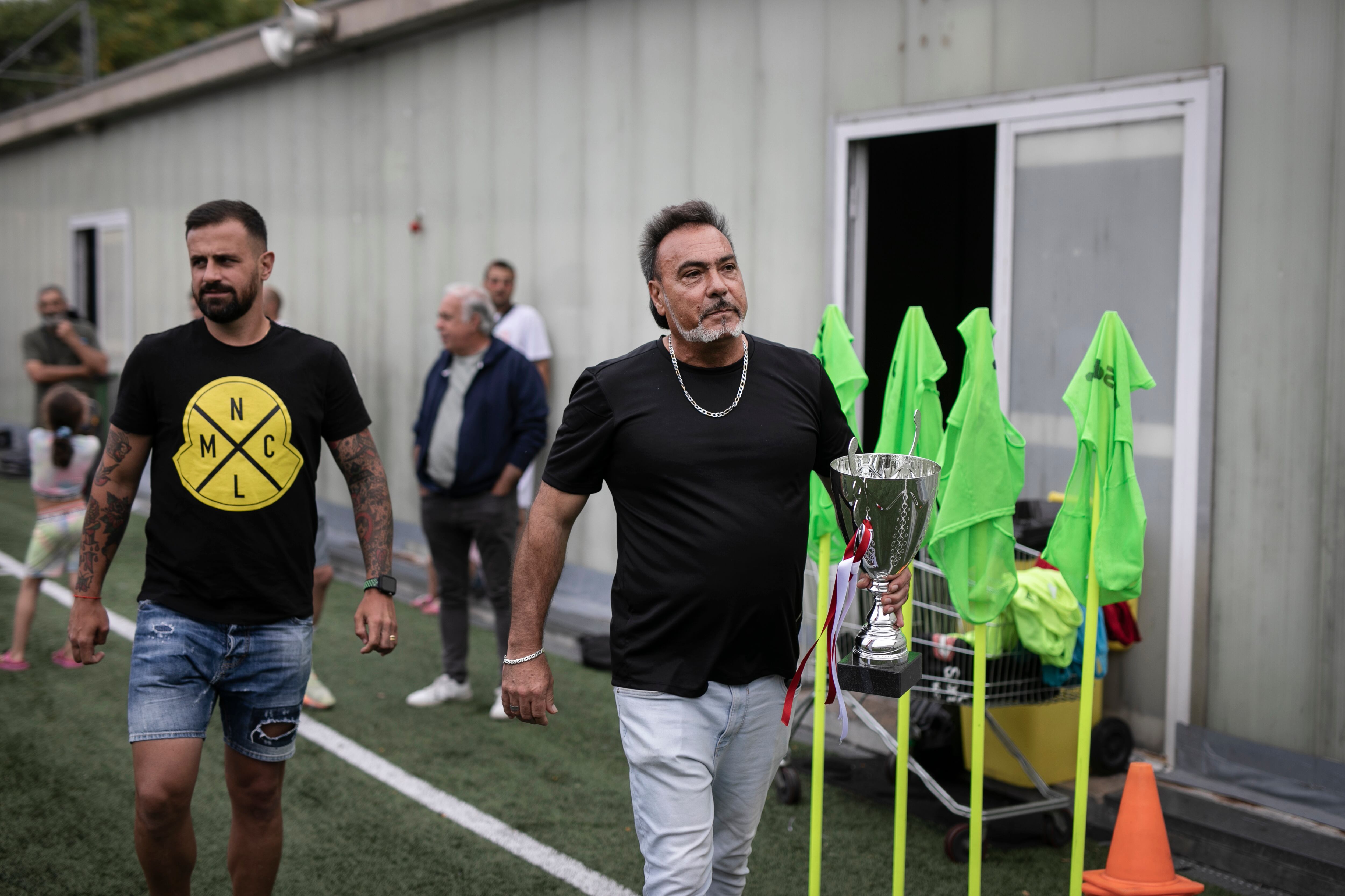 En la imagen Toni Porto, fundador del CF Tramontana acompaña Javier Márquez, ex jugador del Espanyol, para entregar un título a uno de los equipos de CF Tramontana en el campo de futbol del Pabellón Olímpico Municipal La Mina. 