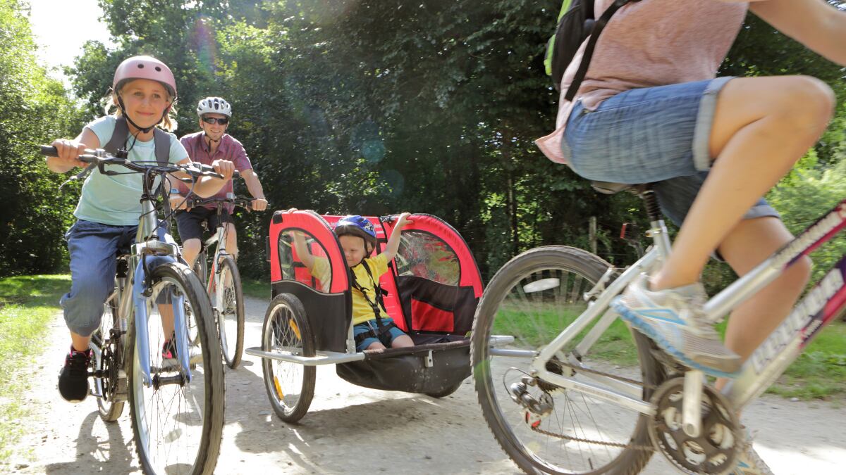 Una persona lleva a un niño en una bicicleta con remolque.