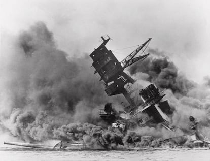 USS Arizona belches smoke as it topples over into the sea during a Japanese surprise attack on Pearl Harbor