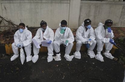 Empleados sanitarios descansan tras examinar a los vecinos de un edificio residencial de Mumbai (India) para detectar a posibles casos de coronavirus. El primer ministro de la India, Narendra Modi, ha advertido este domingo que 'el coronavirus es tan peligroso como al principio' y ha pedido a la población que utilice mascarilla, ante la aceleración de la propagación de la pandemia en el país asiático.