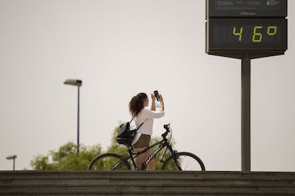 Una mujer hace una foto al indicador de temperatura en Sevilla, este sábado. Será un episodio "breve, pero intenso", advierte la Agencia Estatal de Meteorología (Aemet), que atribuye estas altas temperaturas, que rozan casi el récord de los últimos años en algunas zonas, a la entrada por el sur de aire de procedencia africana que sé irá extendiendo por todo el territorio, excepto por el extremo noroeste peninsular.