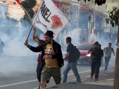 Protestors run as riot police fire tear gas at them.