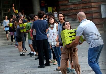 Un grup de persones fan una cadena per entrar material dins de l'escola elemental Collaso i Gil de Barcelona.