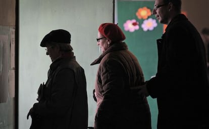 Tres búlgaros se preparan para votar hoy en Sofía.