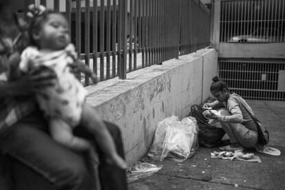 Adriana busca comida en el interior de una bolsa de basura mientras una amiga sostiene a su hija de año y medio.  No muy lejos de allí se encuentra el Palacio de Miraflores, sede del Gobierno de Venezuela y despacho oficial del presidente de la República, donde se toman las grandes decisiones.