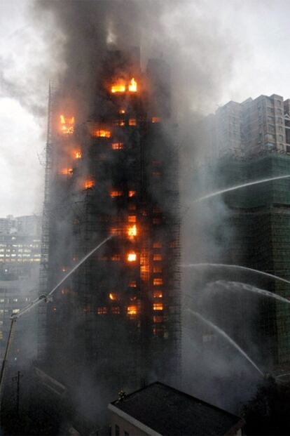 Los equipos de bomberos tratan de apagar el incendio declarado en un edificio de Shanghái.