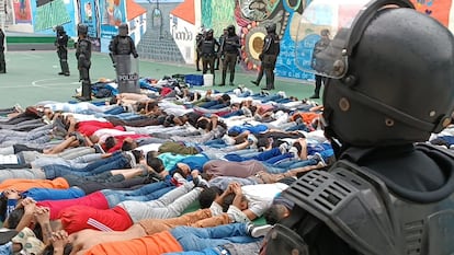 Decenas de presos, vigilados por agentes de la policía, acostados en el patio de la cárcel del Inca de Quito.