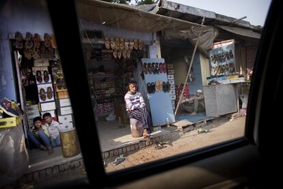 "Contradicciones: vender calzado estando descalzos... Ofrecer ayuda a cambio de algo". Dos hombres y dos niños sentados en la entrada de un comercio de zapatos en una zona comercial de Agra.
