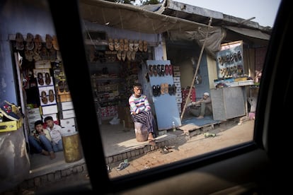 "Contradicciones: vender calzado estando descalzos... Ofrecer ayuda a cambio de algo". Dos hombres y dos niños sentados en la entrada de un comercio de zapatos en una zona comercial de Agra.
