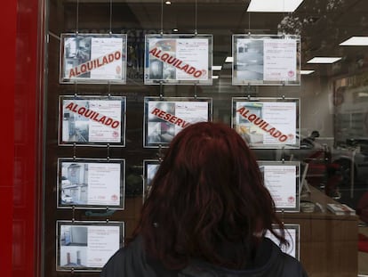 Una mujer consulta los carteles de venta y alquiler con las ofertas de pisos y chalés en el escaparate de una agencia inmobiliaria en Madrid. 
 
 