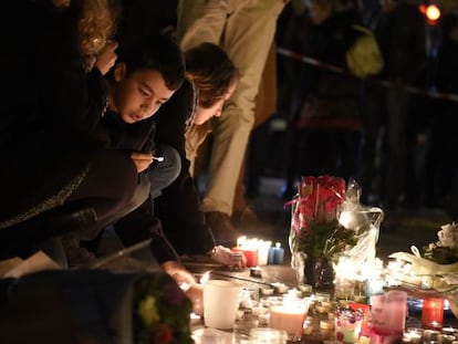 Um grupo de pessoas, entre elas um menino, colocam flores e velas nas proximidades da sala Bataclan, em Paris, um dos cenários dos ataques jihadistas cometidos na noite de 13 de novembro de 2015.