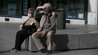 Dos personas con mascarillas en una calle de Madrid.