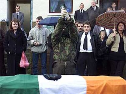 Un pistolero encapuchado del IRA real dispara al aire con una pistola durante el funeral de uno de sus colegas.