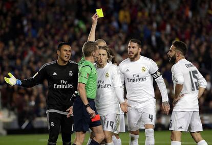 El árbitro Alejandro Hernández saca tarjeta amarilla al defensa del Real Madrid Daniel Carvajal (d) durante el encuentro.