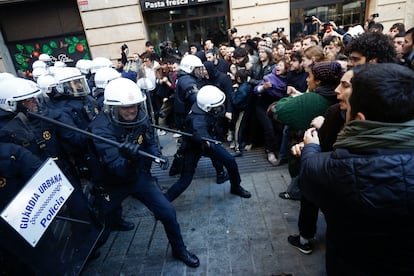 Agentes de la Guardia Urbana de Barcelona impiden el avance de las decenas de personas que protestan ante el dispositivo puesto en marcha a primera hora de esta ma?ana para recuperar el edificio conocido como la Antiga Escola Massana.