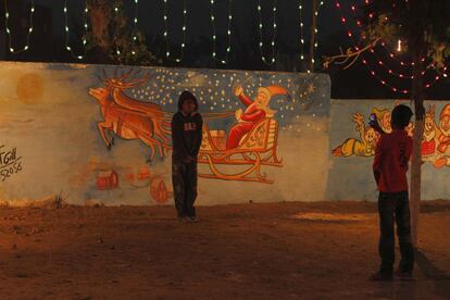 Un niño se fotografía junto a una pintura de Papa Noel en el barrio cristiano de Islamabad, Pakistán.