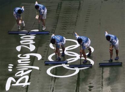 Voluntarios secan la pista de tenis de Pekín