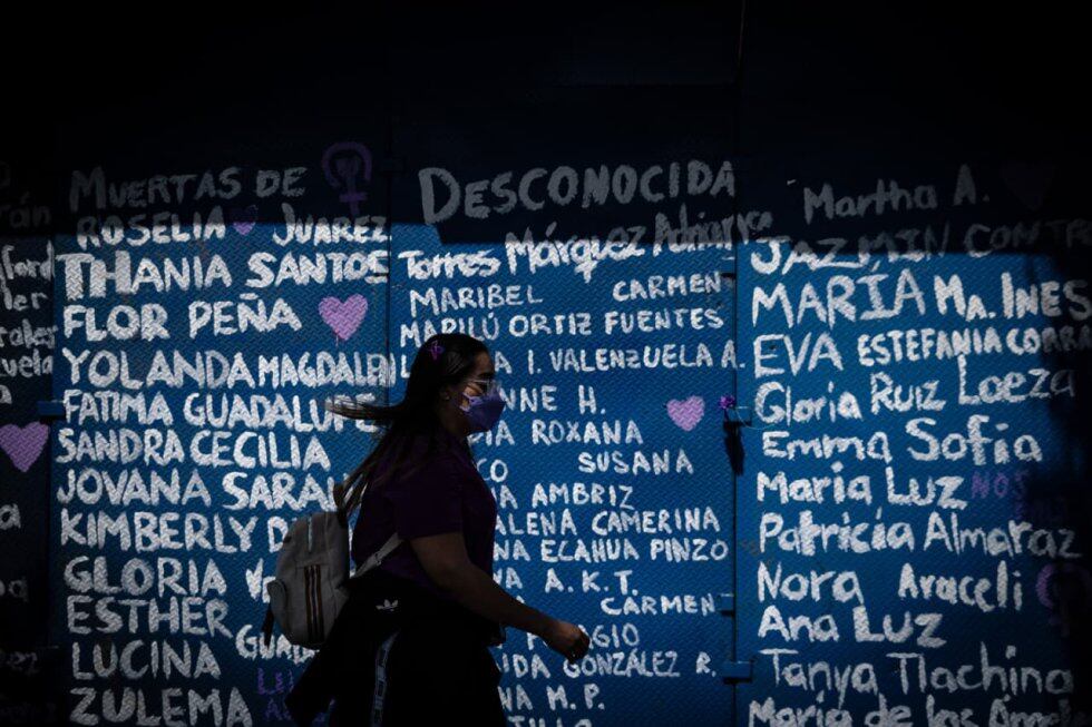 Una mujer camina frente a la valla que blindaba Palacio Nacional de las manifestantes, en la marcha del 8 de marzo de 2021.