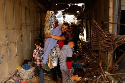 Un hombre porta sus enseres mientras se abre paso entre los casquetes de un edificio destruido por un ataque israelí en Jan Yunis. 