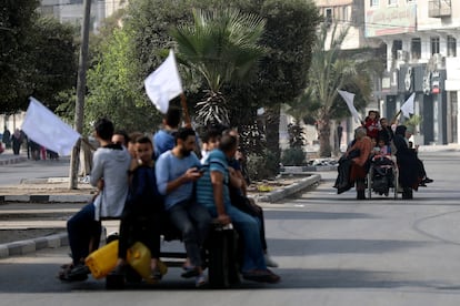 Palestinos huyen de la ciudad de Gaza montados en carros tirados por burros, mientras levantan banderas blancas para evitar ser disparados, este miércoles en el barrio de Al Rimal.