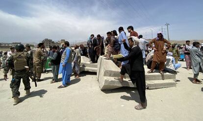 Un grupo de afganos espera a las afueras del aeropuerto en Kabul, este martes.
