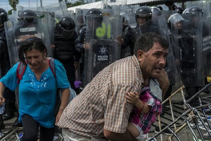 Um homem protege seu bebê após que a polícia mexicana lançar gás para conter os migrantes na ponte Rodolfo Robles.