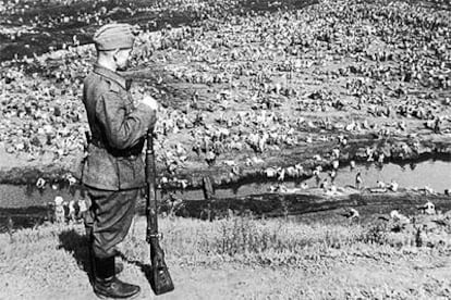 Un soldado alemán vigila un campo de concentración a cielo abierto con presos soviéticos en la retaguardia del frente ruso.