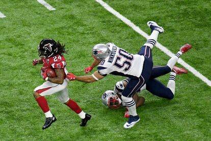 Devonta Freeman, de los Atlanta Falcons, corre ante los jugadores de los New Englan Patriots, Duron Harmon y Rob Ninkovich,en el primer cuarto del partido.