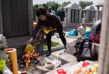 A woman burns offerings at a grave during the annual "Qingming" festival, or Tomb Sweeping Day, at a public cemetery in Shanghai on April 4, 2016.
During Qingming, Chinese traditionally tend the graves of their departed loved ones and often burn paper offerings to honour them and keep them comfortable in the afterlife. / AFP PHOTO / JOHANNES EISELE