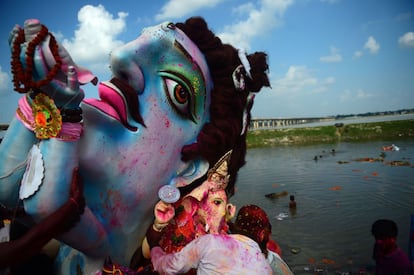 Devotos hindúes cargan con un ídolo que representa a la deidad hindú Ganesha para sumergirla en un estanque temporal cerca de Sangam en Allahabad (India).