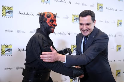 El presidente de la Junta de Andalucía, Juanma Moreno, saluda a un actor vestido como el personaje Darth Maul, de 'Star Wars'.