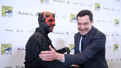El presidente de la Junta de Andalucía, Juanma Moreno, saluda a un actor vestido como el personaje Darth Maul, de 'Star Wars'.