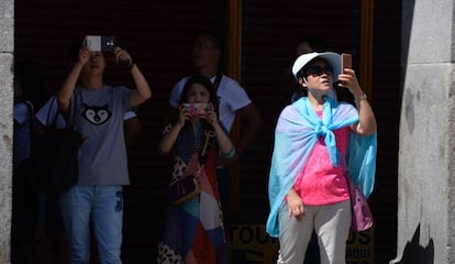 Varios turistas hacen fotografías con su teléfono móvil en El Centro de Madrid.