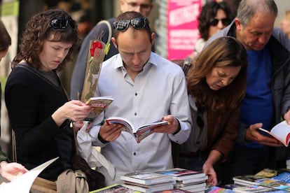 Ciudadanos en un tenderete de libros en la Rambla de Girona.