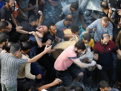 Ciudadanos palestinos rescatan a heridos de entre los escombros tras el ataque israelí al campo de refugiados de Magazi, en la franja de Gaza este domingo.