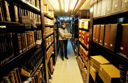 Uno de los pasillos en los que se acumulan los volúmenes de la Biblioteca Nacional, que cada año recibe cerca de 900.000 nuevos documentos. En la imagen, una de las empleadas del centro, en el que trabajan unas 1.000 personas.