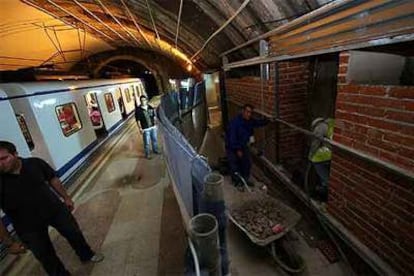 Una endeble valla separa a los pasajeros del metro de los operarios (uno de ellos sin casco) de las obras de reforma de Legazpi.