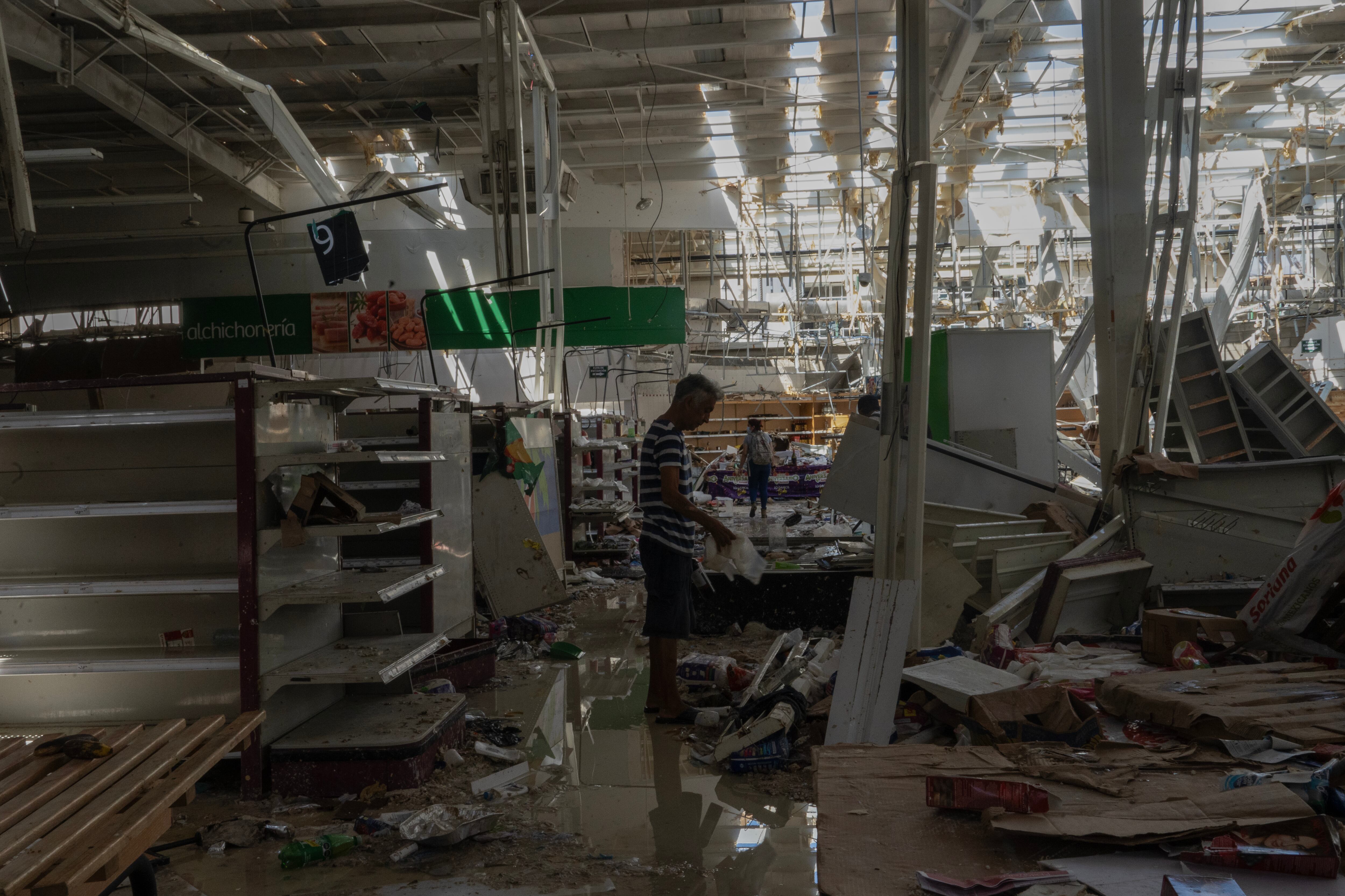 Un hombre busca alimentos de un supermercado saqueado en Acapulco.