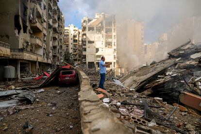 Un hombre graba con su móvil los daños causados en un edificio colapsado tras un ataque aéreo israelí en Beirut, este martes.