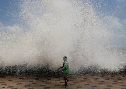 Una niña se moja con una gran ola durante la marea alta en Mumbai, India.