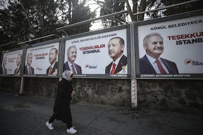 Una mujer pasa junto a los carteles electorales de Binali Yildirim (izquierda), candidato a la alcaldía de Estambul por el Partido de Justicia y Desarrollo (AKP), junto al presidente de Turquía, Recep Tayyip Erdogan, un día después de las elecciones locales en Estambul. El partido opositor socialdemócrata CHP ha arrebatado a la formación del presidente el poder en Ankara y lidera el recuento en Estambul.