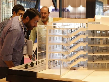 Visitantes del Salón Inmobiliario de Madrid observan una de las maquetas de viviendas expuesta en la feria.