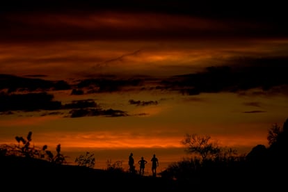 People stand atop a rock formation to watch the sunset, Sunday, July 30, 2023, in Phoenix. Phoenix hit its 31st consecutive day of at least 110 degrees Fahrenheit (43.3 Celsius).