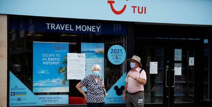 Dos personas con mascarilla frente a una tienda del turoperador Tui en Chester, Reino Unido.