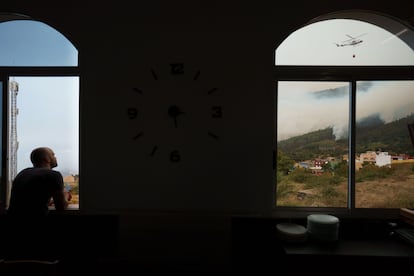 Un hombre observaba desde una ventana de un restaurante de Aguamansa, en el municipio de La Orotava, los trabajos de los helicópteros para extinguir el incendio forestal, el viernes.