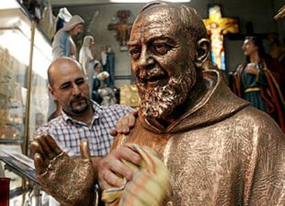 Un comerciante romano saca brillo a una estatua del padre Pío de Pietrelcina.