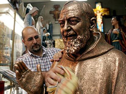 Un comerciante romano saca brillo a una estatua del padre Pío de Pietrelcina.