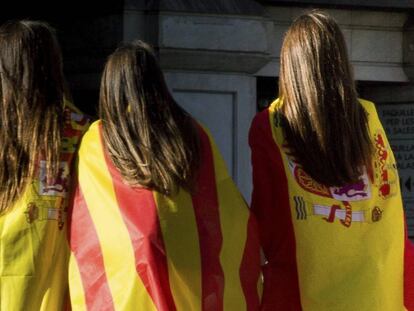 Tres j&oacute;venes con banderas espa&ntilde;olas y catalanas tras la manifestaci&oacute;n celebrada el pasado d&iacute;a 29 en Barcelona. 
