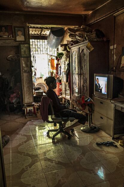 Una mujer ve la televisión en su apartamento, oscuro pero fresco, evitando el calor abrasador y la humedad de fuera.